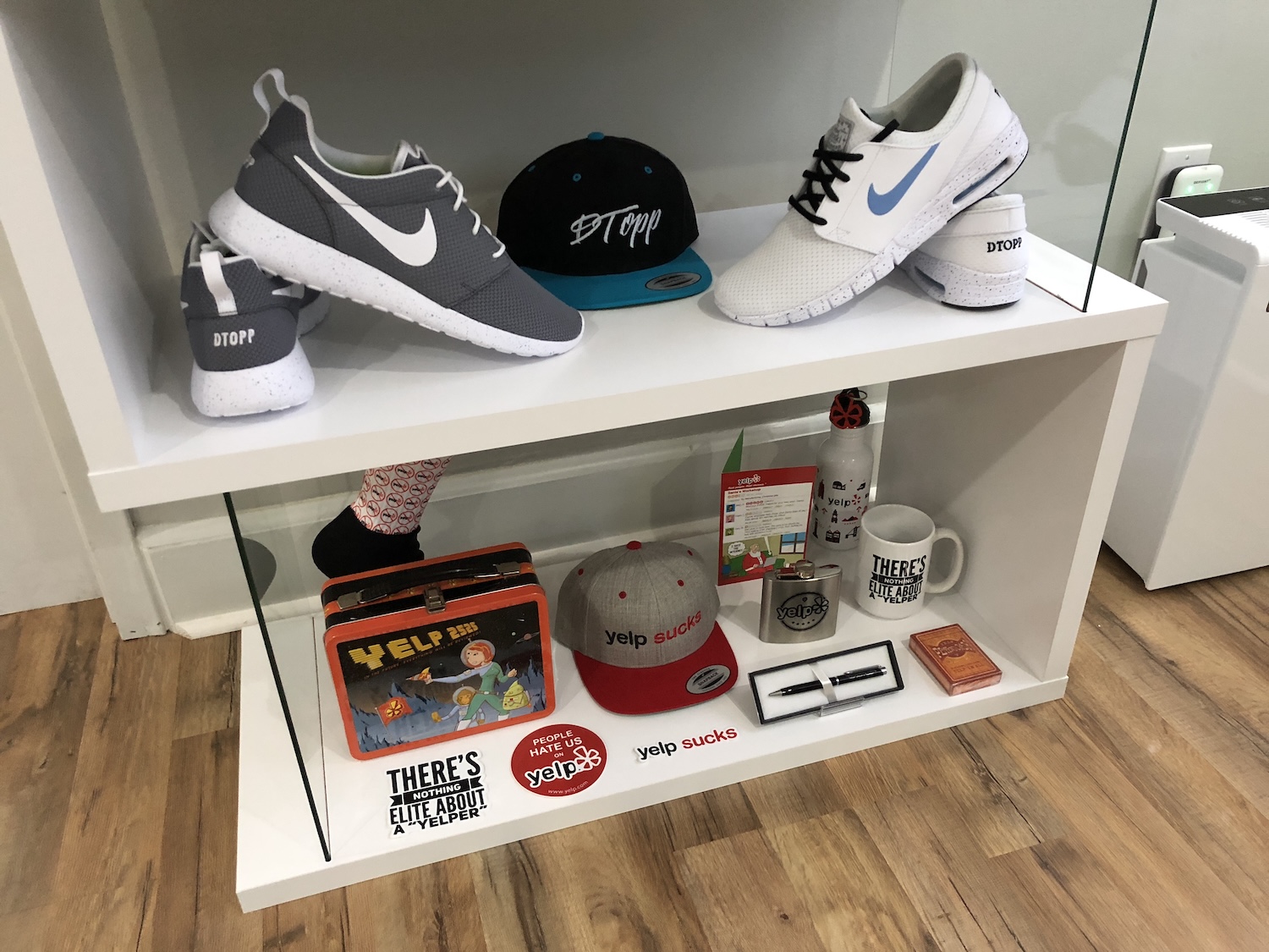 Display shelf with DTopp-branded sneakers and a hat above a collection of Yelp-themed items