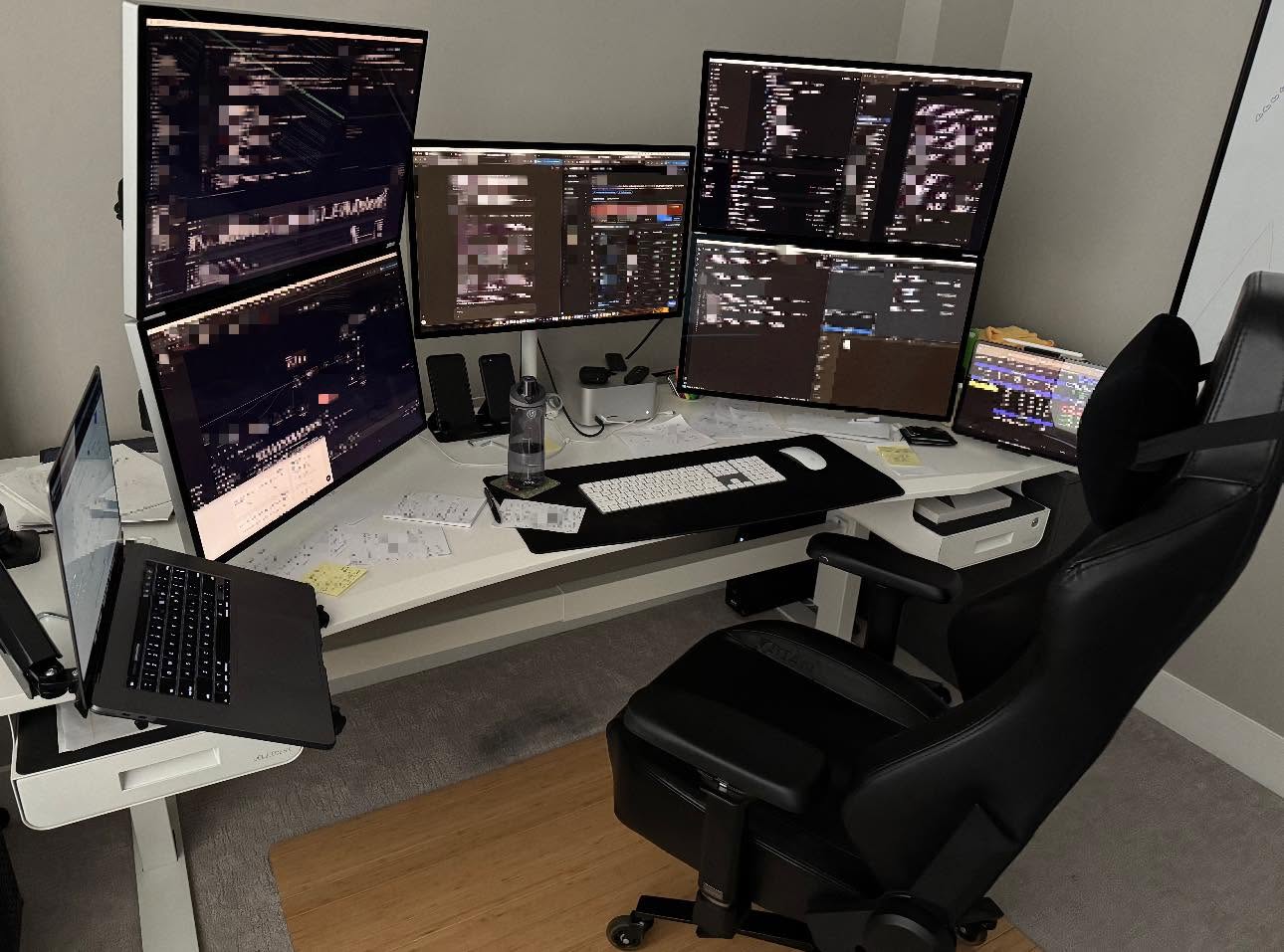 David Topping’s desk: five monitors, a laptop, and an iPad on a white corner desk